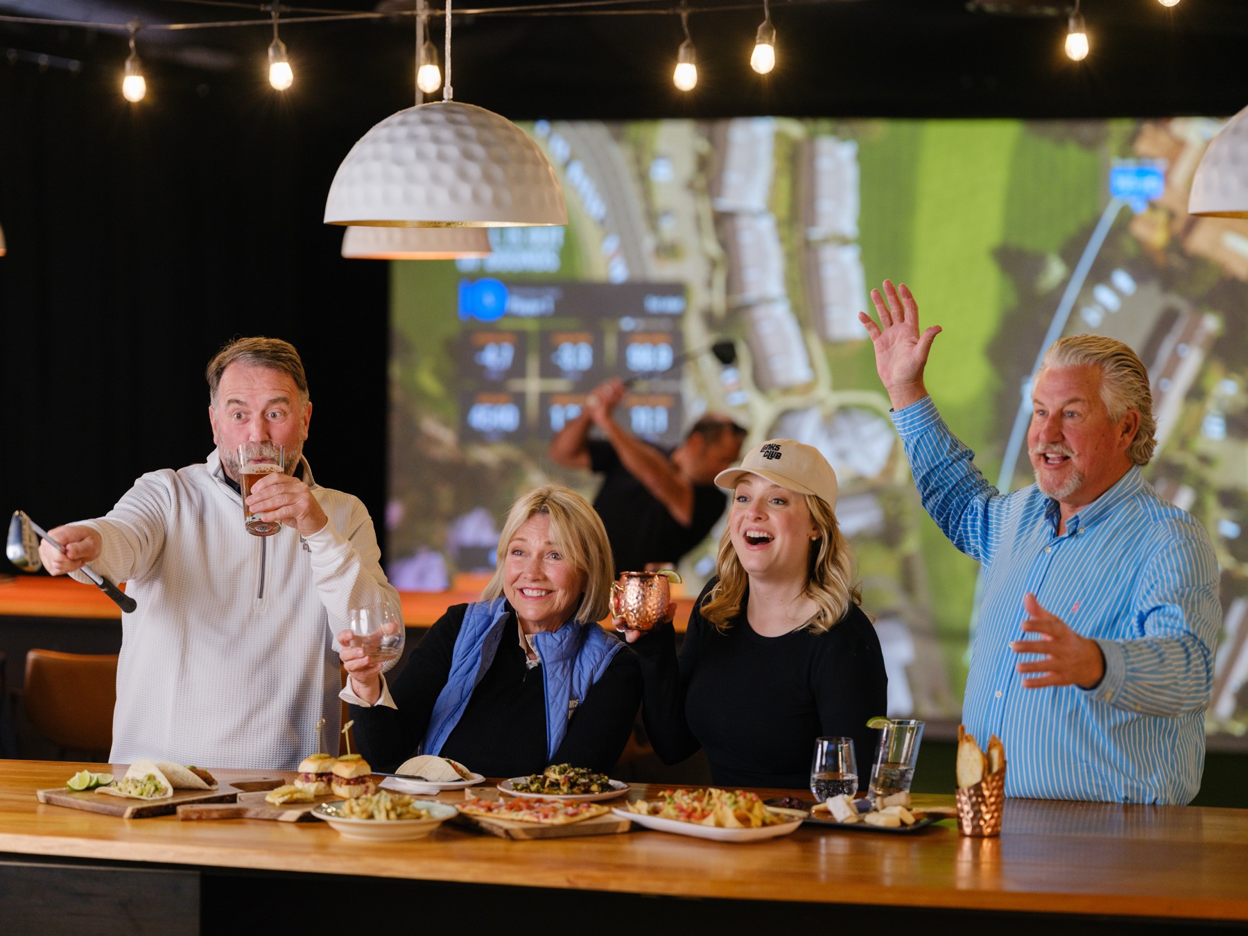 A group celebrating with food and drinks at the Links Club bar