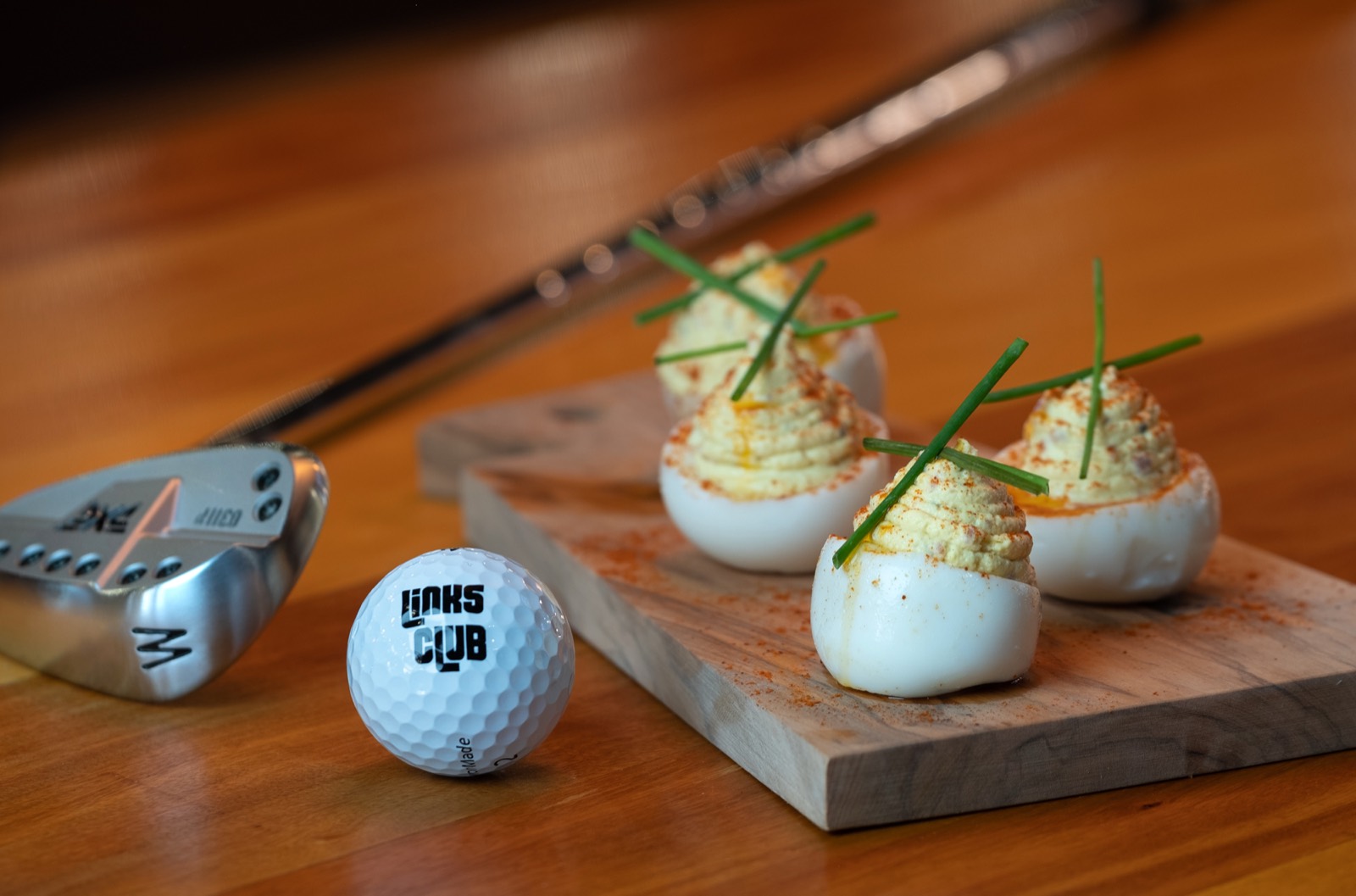 Deviled eggs plated on a board beside a Links Club golf ball