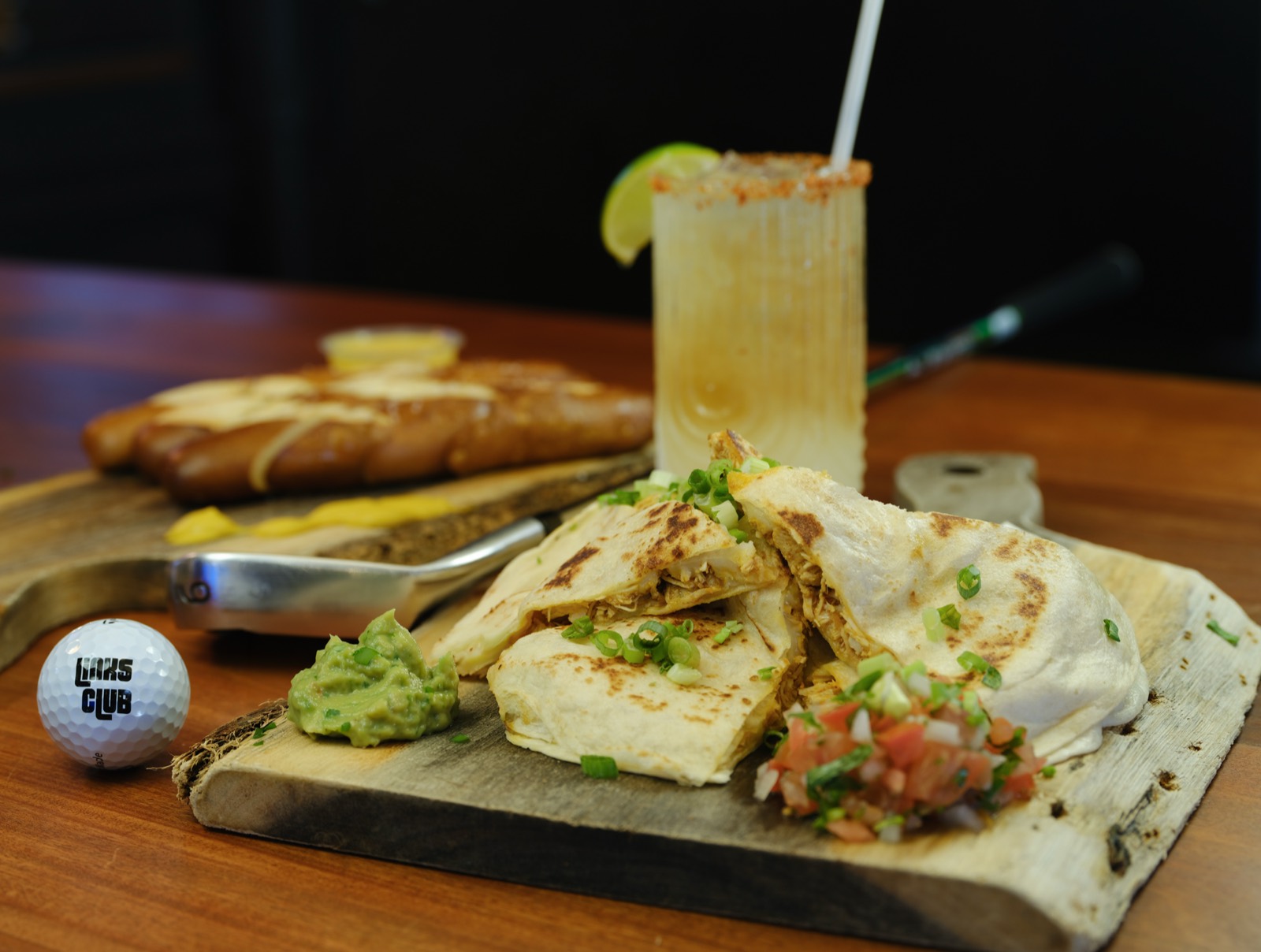 Chicken quesadilla with guacamole and pico de gallo on a wood board with a spiced-rim cocktail
