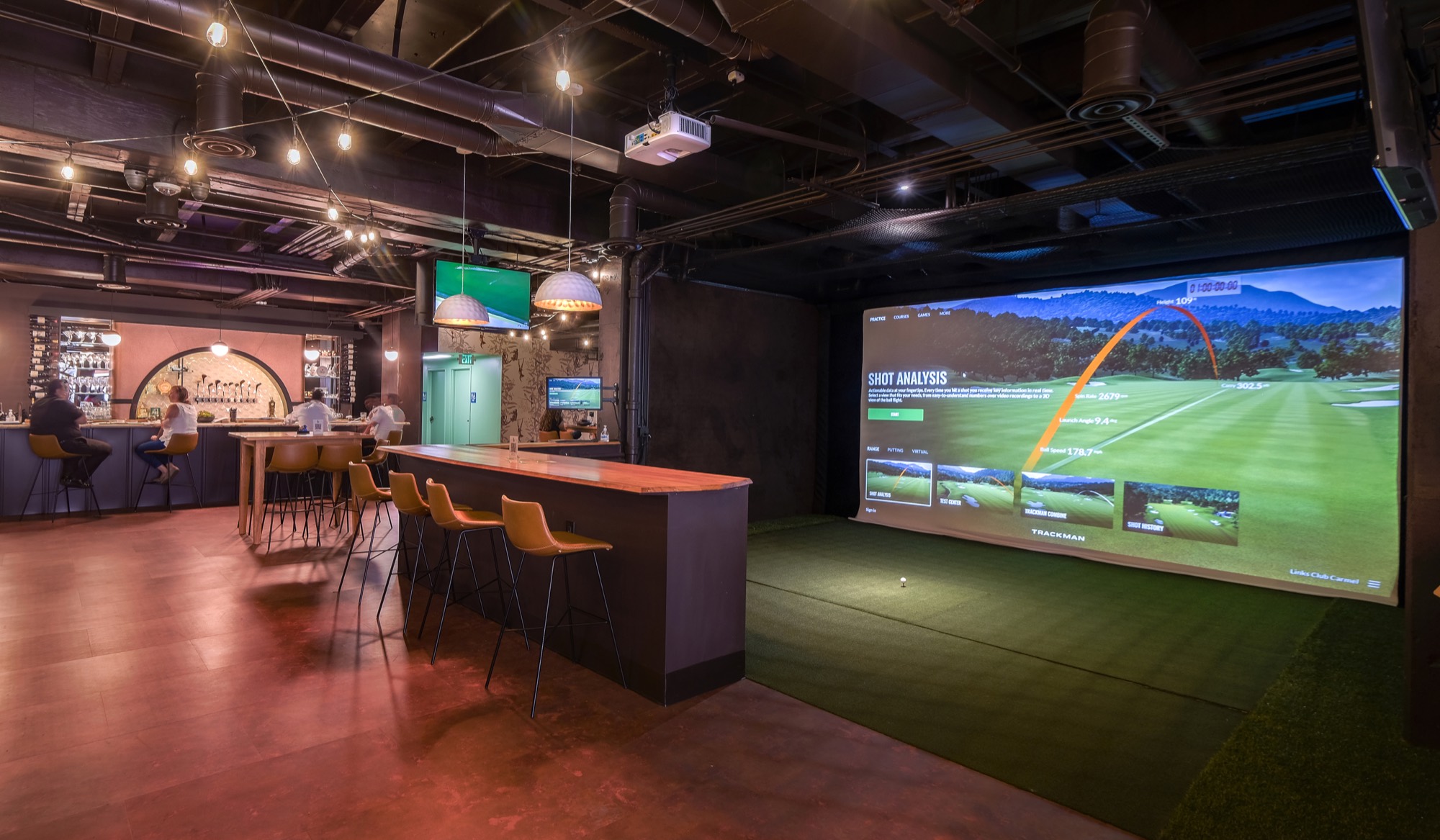 The full Links Club floor — bar, tables, and simulator bays under warm lighting